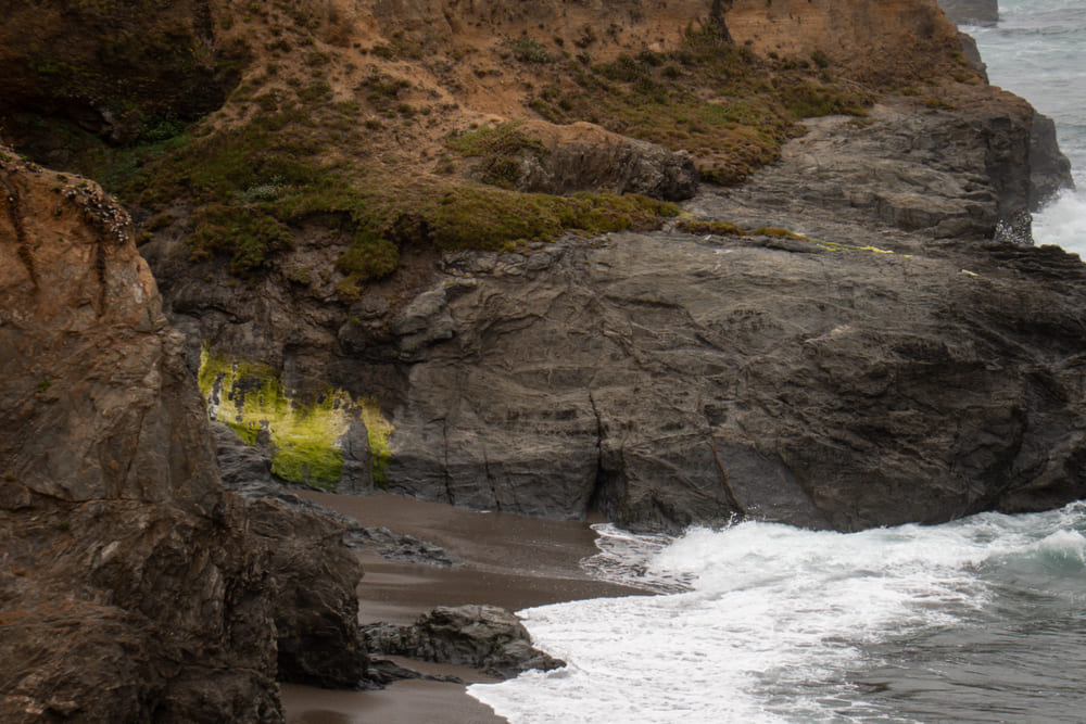 Sea cliffs and a hidden cove on the Mendocino coast, surf breaking on dark sand